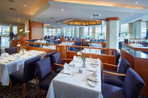 a restaurant with white tables and blue chairs at Parkhotel Pforzheim in Pforzheim