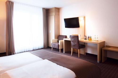 a hotel room with a bed and a desk at Lanzcarré Hotel Mannheim, a member of Radisson Individuals in Mannheim