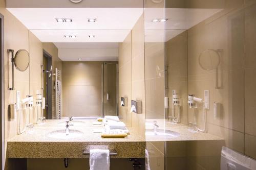 a bathroom with two sinks and a large mirror at Lanzcarré Hotel Mannheim, a member of Radisson Individuals in Mannheim