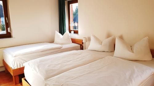 Duas camas num quarto com lençóis e almofadas brancos em Ferienwohnung im Haus Wizlaw mit Balkon im 1 OG em Ostseebad Sellin