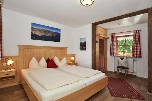 シェーナウ・アム・ケーニッヒスゼーにあるFerienwohnung Grünsteineckのベッドルーム1室(白いシーツと赤い枕の大型ベッド1台付)