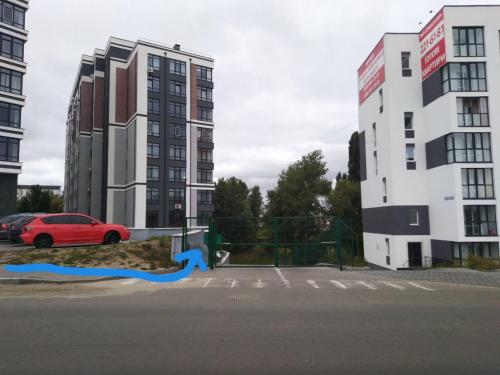 a red car parked next to two tall buildings at Двокімнатна , Троєщина, район 2, ТЦ район in Kyiv