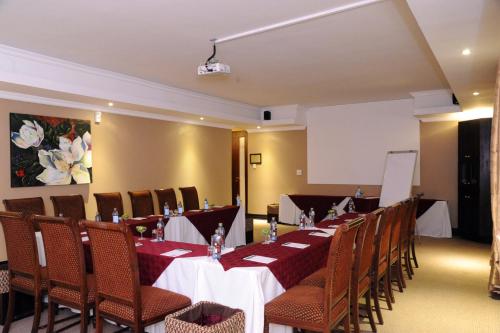 a conference room with tables and chairs and a screen at Anta Boga Hotel in Bloemfontein