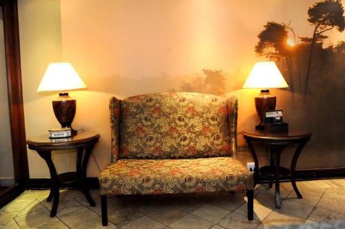 a room with two lamps on tables and a chair at Anta Boga Hotel in Bloemfontein