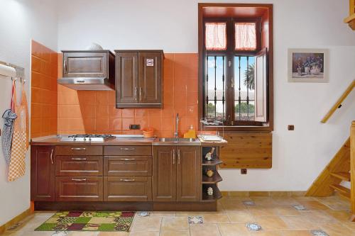 een keuken met houten kasten, een wastafel en een raam bij La Escuelita in Los Valles
