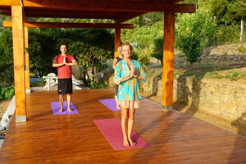 un hombre y una mujer haciendo yoga en una terraza de madera en Villa Shanti Yoga & Meditation en Marciana