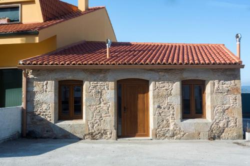 una pequeña casa de piedra con techo de baldosas rojas en Casas Mar de Fisterra, en Finisterre