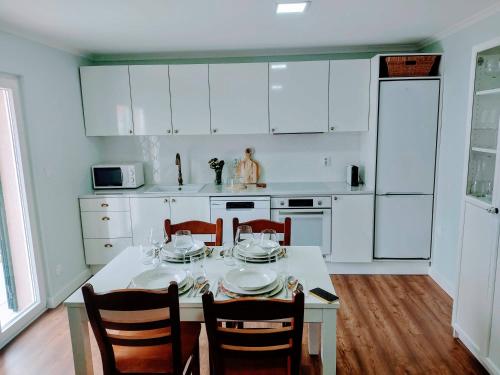 a kitchen with a table with chairs and white cabinets at Casa de Vila Seca in Peso da Régua