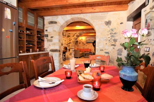 una mesa con un mantel rojo y un jarrón con flores en Afroditi Traditional Villa, en Yiannioú