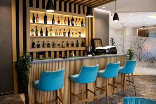 un bar con sillas azules y botellas de vino en NEW Garni Hotel FILIA, en Nova Pazova