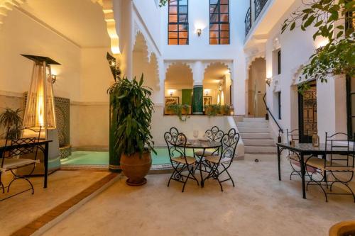 a room with tables and chairs and a potted plant at Riad Hart Essoura in Marrakech