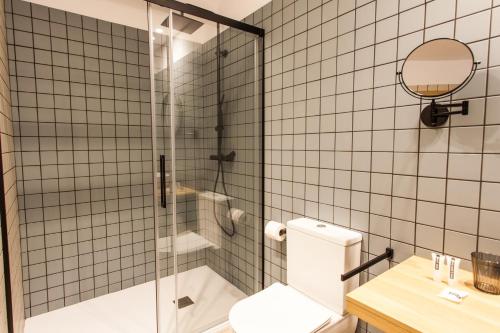 a bathroom with a toilet and a glass shower at Hospedium H Cabo Sport in Finisterre
