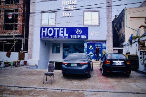 Hotel Tulip Inn في لاهور: سيارتين متوقفتين في موقف امام الفندق