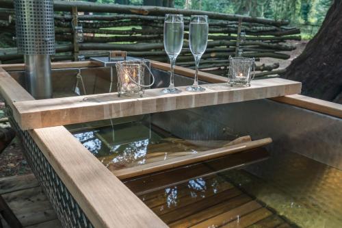 two glasses of wine on a wooden table with water at 1-Bed Cabin 2 adults Wood Burning Hot Tub & Fire in Carluke