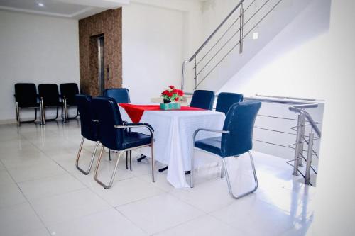 a dining room with a white table and blue chairs at Hotel Tulip Inn in Lahore