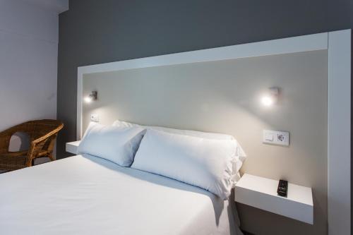 a bedroom with a white bed and a chair at Hospedium H Cabo Sport in Finisterre