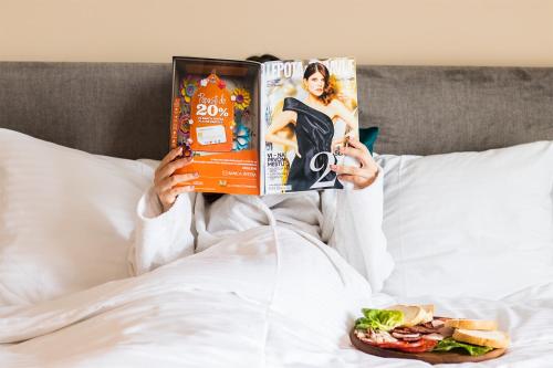 a person laying in bed reading a magazine at Garni Hotel FILIA in Nova Pazova
