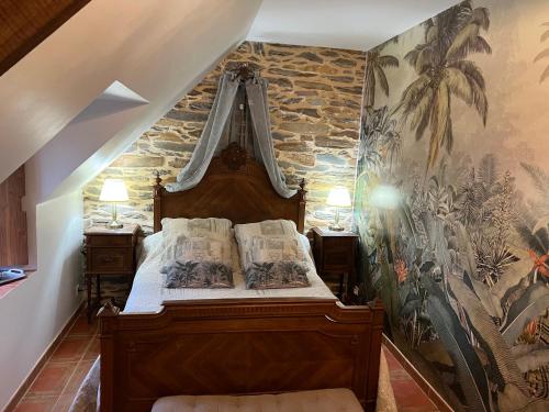 - une chambre avec un lit en bois et un mur en pierre dans l'établissement Le Clos Saint Fiacre, à Carentoir