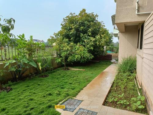 a backyard with a yard with grass and a fence at Neville's Villa - Pet friendly with Pool in Alibaug