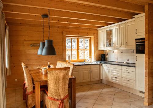 a kitchen with a table and chairs and a kitchen with white cabinets at Luxus Blockhaus Willingen Sonnenhang Lodge B in Willingen