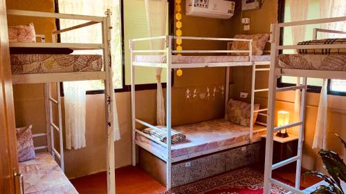 a room with three bunk beds in a room at ROOTSVILLA VAGATOR - Longstays, Coworking Backpacker's Hostel in Vagator