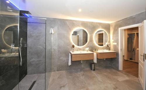 a bathroom with two sinks and two mirrors at Hotel Salobreña Suites in Salobreña