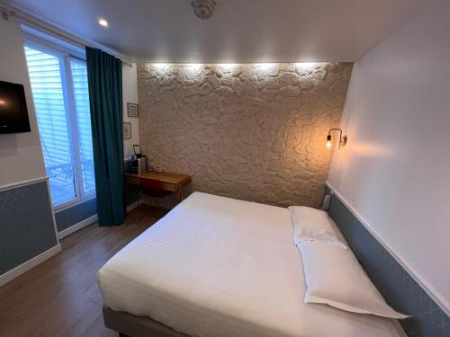 a bedroom with a white bed and a wall at Hôtel Tilde in Paris