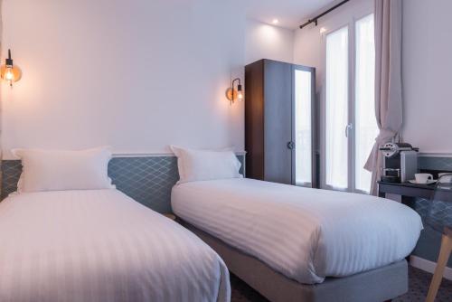 a hotel room with two beds and a window at Hôtel Tilde in Paris