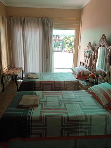 a hotel room with two beds and a window at De la Rose Guesthouse in Lephalale