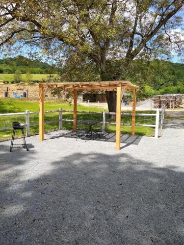 a wooden shelter with a picnic table and a bench at Bienvenue au Relais des Meilles in Caudebec-en-Caux