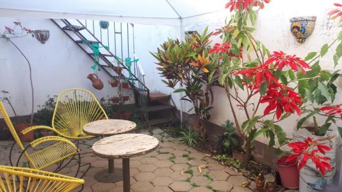 un patio con 2 mesas, sillas y plantas en Casa Santita Por Habitación, en Santa María del Tule