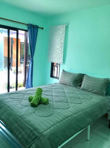 a green teddy bear sitting on top of a bed at KOOK BUNGALOW in Koh Mook