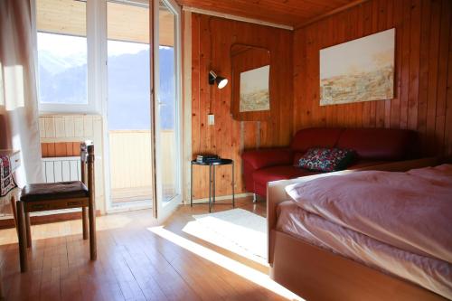 a bedroom with a bed and a couch and windows at Hugo & Rosa -Huusa im Bregenzerwald in Egg