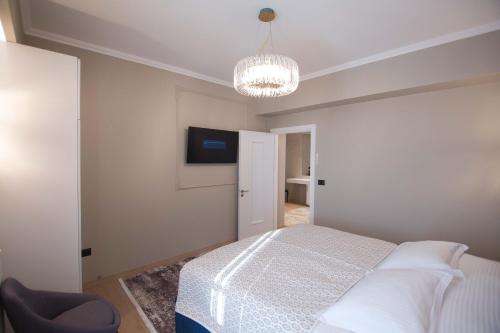 a bedroom with a bed and a television and a chandelier at Sky Hotel Korce in Korçë