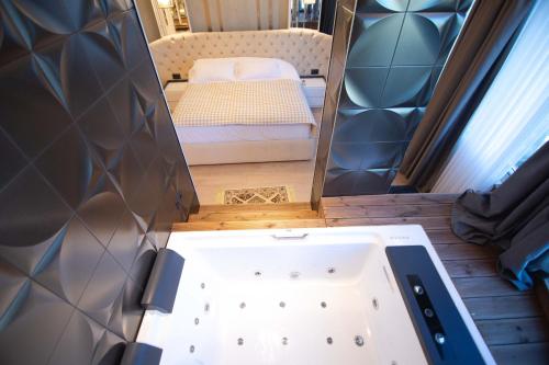 a bathroom with a tub and a bed in a room at Sky Hotel Korce in Korçë