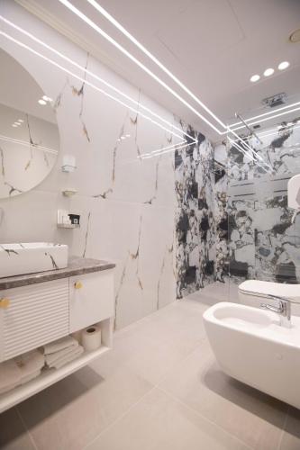 a white bathroom with a sink and a tub at Sky Hotel Korce in Korçë
