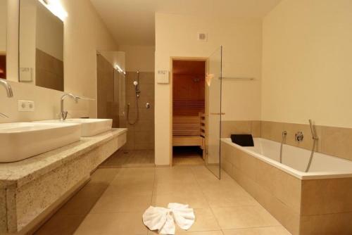 ein Badezimmer mit zwei Waschbecken, einer Badewanne und einer Dusche in der Unterkunft Panorama Chalet in Mittersill