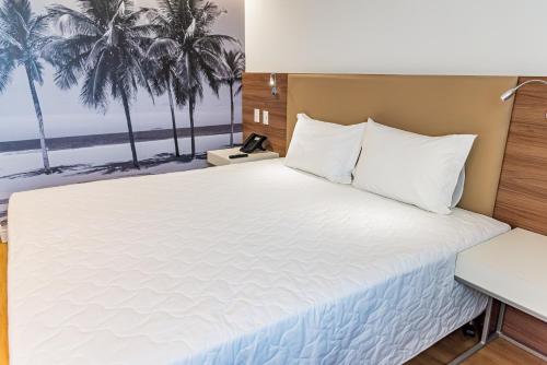 - une chambre avec un grand lit et des palmiers dans l'établissement Rio Hotel by Bourbon Maringá, à Maringá