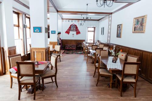 un ristorante con tavoli e sedie e un uomo in piedi sullo sfondo di Casa Marta a Sîmbăta de Sus