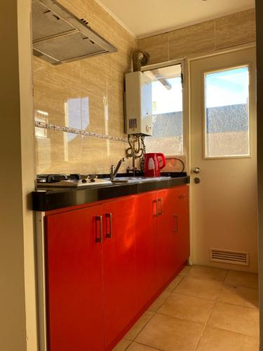 een keuken met rode kasten en een wastafel bij Casa Patagonia #1015 in Coihaique