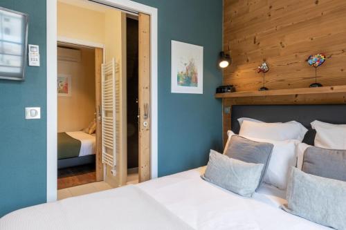une chambre avec un lit blanc avec une tête de lit en bois dans l'établissement ALPES Annecy Rent Lodge, à Annecy