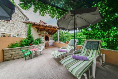 two lawn chairs and an umbrella on a patio at Apartment Akacija in Postira