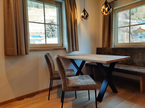 a table and chairs in a room with two windows at ROSENHOF- Premium & Landhaus Apartments & Wellness & Erlebnisbauernhof in Nauders