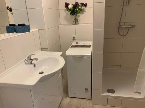 a white bathroom with a sink and a shower at Studio mit Meerblick und großer Loggia - Direktzugang zur Nordsee in Wilhelmshaven