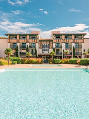 un immeuble avec une piscine devant un immeuble dans l'établissement LE HAMEAU DES VAGUES 4-5 PERS Piscines et Nature à MOLIETS, à Moliets-et-Maa