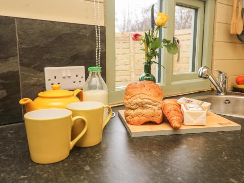una encimera de cocina con 2 tazas, pan y cruasanes en Hare en Keighley