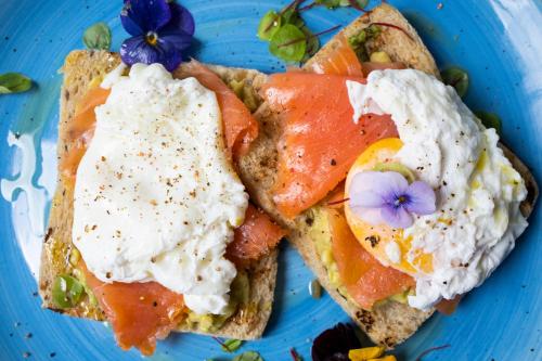a blue plate with two pieces of toast with eggs and tomatoes at Hotel Quadrifoglio in Pontecagnano