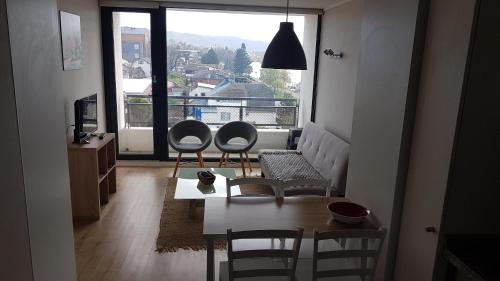 a living room with two chairs and a table and a large window at Departamento costanera vista al río y con la mejor ubicación de la ciudad in Valdivia
