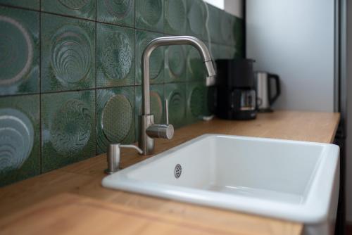 a white sink in a kitchen with green tiles at 80 Quadratmeter Komfortzone in Braunlage