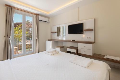 a white bedroom with a large bed and a window at Soothe Hotel in Kalkan
